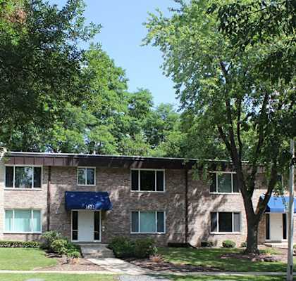 A building with a blue awning is surrounded by trees.