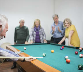 a group of people around a pool table