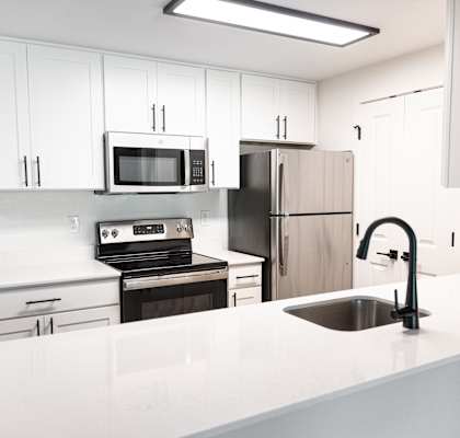 a white kitchen with stainless steel appliances and white counter tops