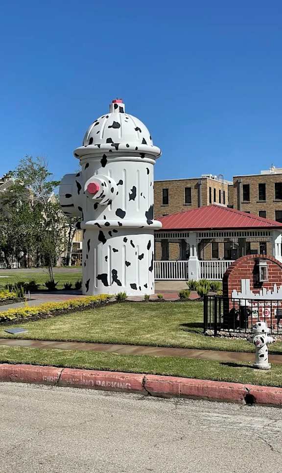A fire hydrant painted to look like a cowboy hat sits in front of a building.