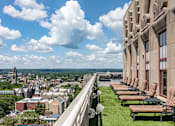Thumbnail 13 of 23 - A view of a city from a high vantage point with a row of lounge chairs on the right.
