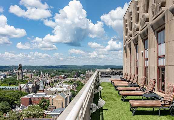 A view of a city from a high vantage point with a row of lounge chairs on the right.