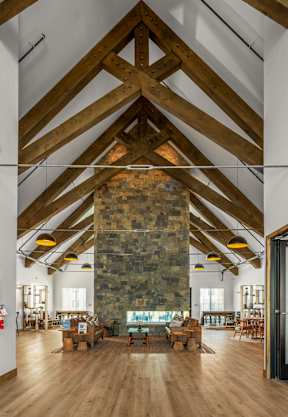 A wooden table with a cloth on it is in the foreground of an indoor space with a stone wall and wooden floors at Silverbrook Apartments Apartments, Kalispell
