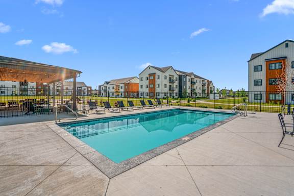 A swimming pool in a sunny day surrounded by chairs.
