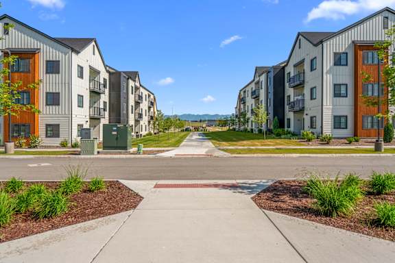 A row of modern apartment buildings with a sidewalk in front.