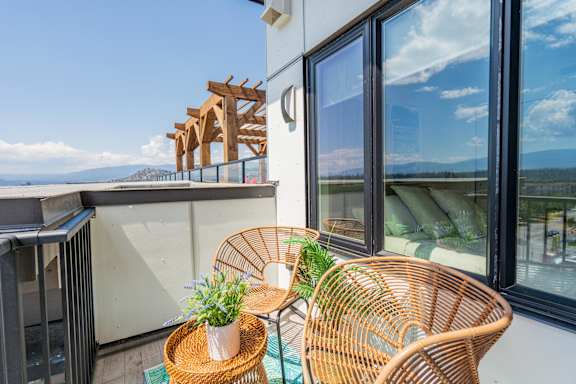 A balcony with a table, two chairs, and a potted plant.