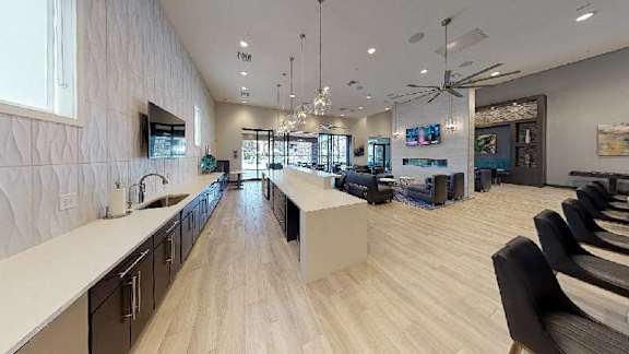 A modern kitchen with a long counter and a dining area with chairs.