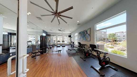 A gym with a wooden floor and a ceiling fan.