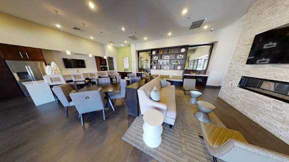 A modern kitchen with a long counter and a dining area with chairs.