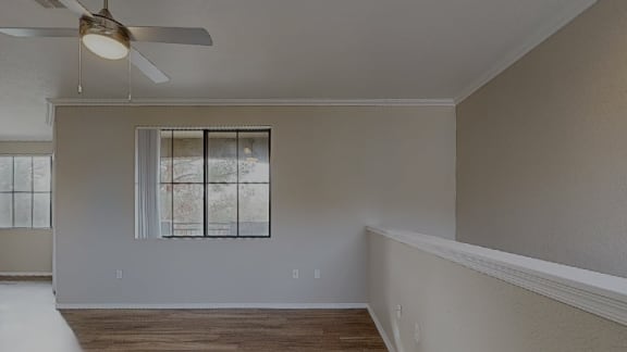 an empty living room with a ceiling fan and a window at The Paseo by Picerne, Arizona 85395