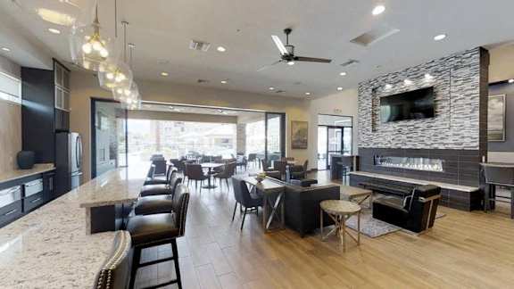 A modern kitchen with a long counter and a dining area with chairs.