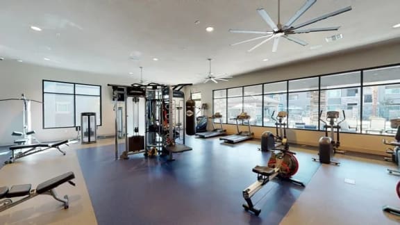 a workout room with weights and other exercise equipment and large windows