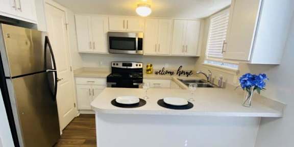 A kitchen with a refrigerator, microwave, oven, and sink.