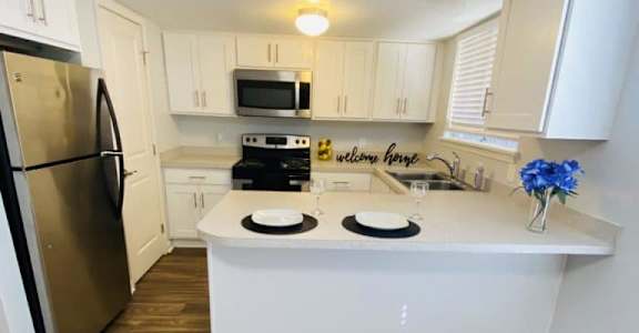 A kitchen with a refrigerator, microwave, oven, and sink.