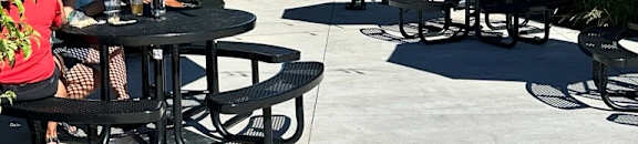 A group of people are sitting at tables under blue umbrellas in a courtyard.
