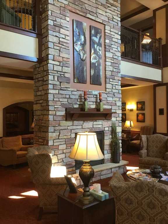 A living room with a stone fireplace and a painting above it.