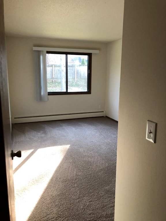 A room with a carpeted floor and a window.