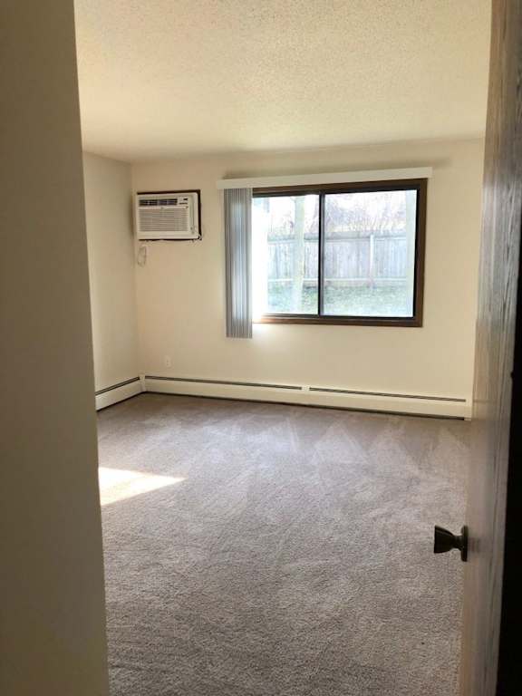 A room with a carpeted floor, a window with blinds, and a door.
