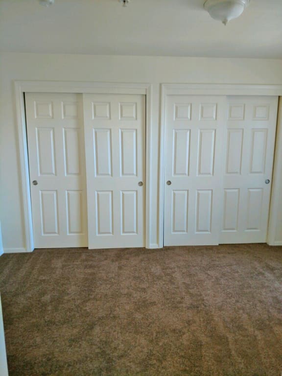 First bedroom showing double closet sliding door.  Flooring is carpet.