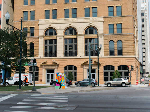 A large, old building with many windows sits on a city street corner.