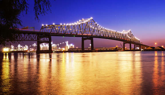 A bridge with lights strung across it over a body of water.