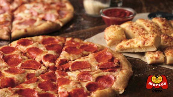 A pizza with pepperoni slices on it is on a wooden table.