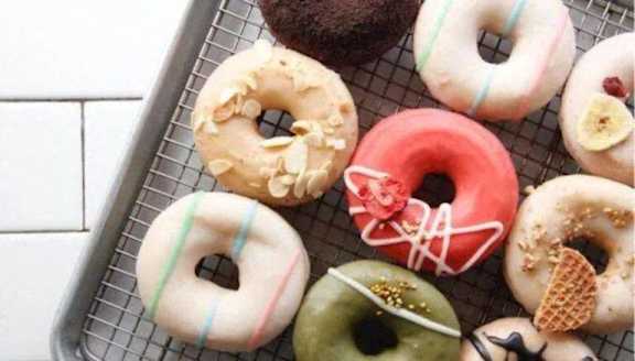 A tray of assorted glazed donuts with different toppings.