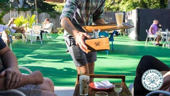 A person is serving drinks to guests at an outdoor event.