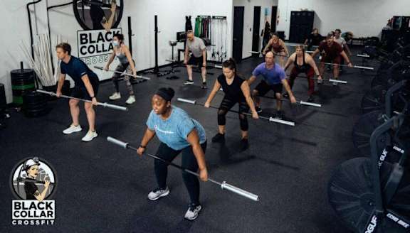 A group of people are participating in a crossfit class at Black Collar Crossfit.