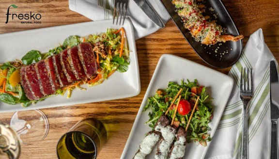 A wooden table with a plate of food and a glass of wine.