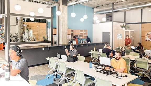 A group of people are working in a modern office space with computers and desks.