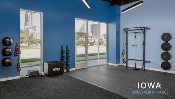 A gym with a blue wall and a sign that says Iowa Spine Performance.