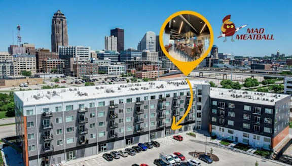 A building with a yellow arrow pointing to a window with a picture of a burger and fries on it.