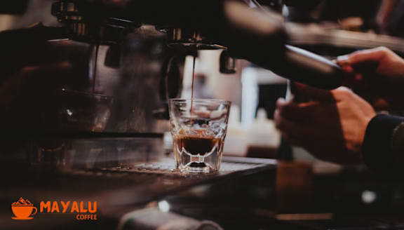 A glass of coffee being poured from a coffee machine.