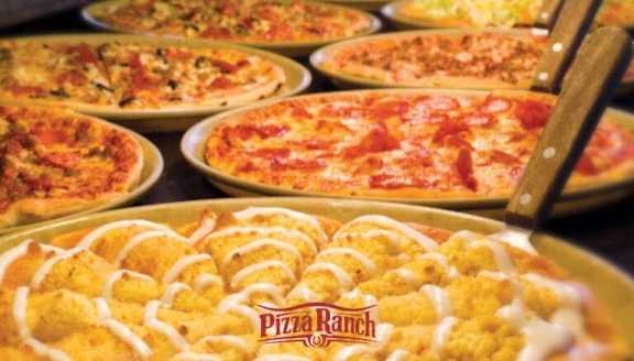A Pizza Ranch pizza with a wooden spatula is in the foreground.