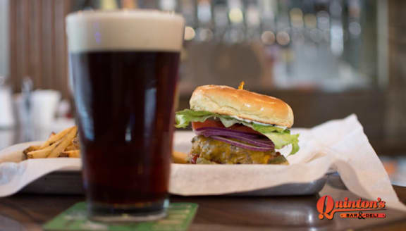 A burger and fries are on a table with a glass of beer.