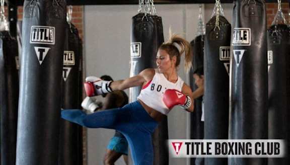 A woman in a boxing class is practicing her kicks.