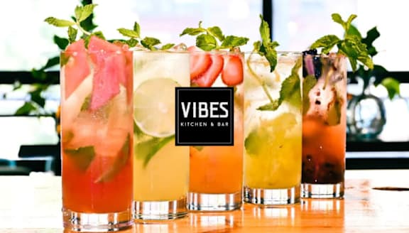 Four glasses of different coloured cocktails with mint leaves on top.