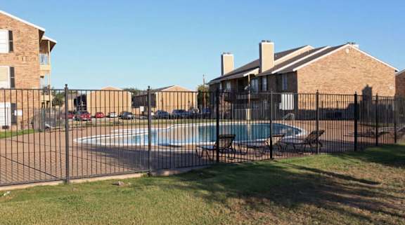 A black fence surrounds a pool in a backyard.