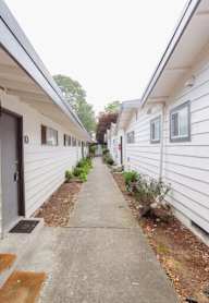 a corridor between two white buildings with a path between them