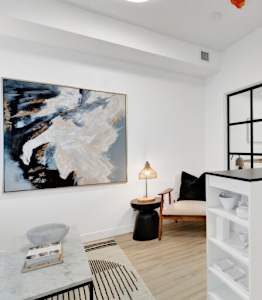 A modern living room with a white sofa and a large abstract painting on the wall.