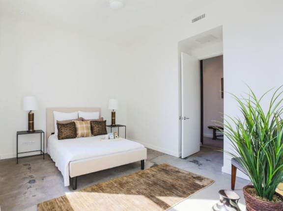 A bedroom with a large bed and a potted plant.