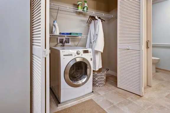 A white washing machine is in a small laundry room.