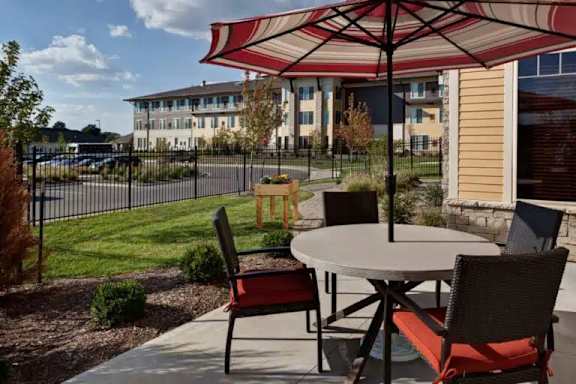 A patio with a table and chairs under a striped umbrella.