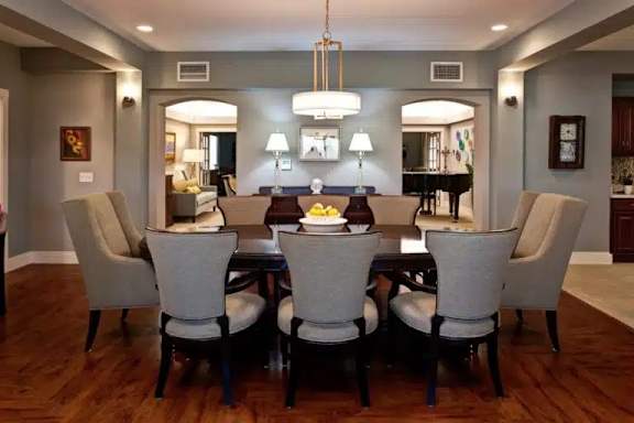 A dining room with a large table and chairs.