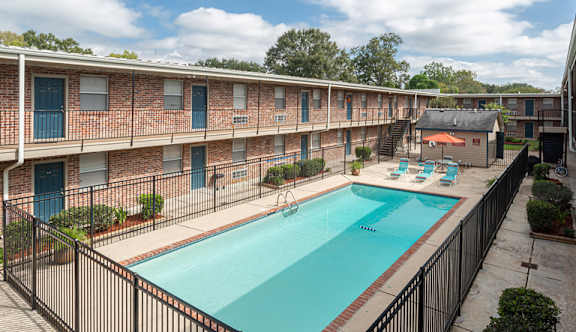 A swimming pool in a courtyard surrounded by a black fence.