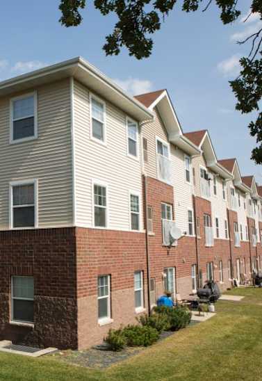 A row of apartment buildings with red brick and beige siding.