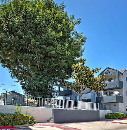 A large grey building with a tree in front of it.