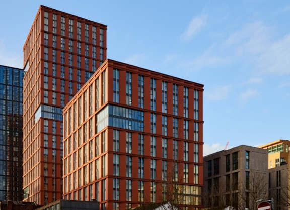 a view of two brick apartment buildings against a blue sky