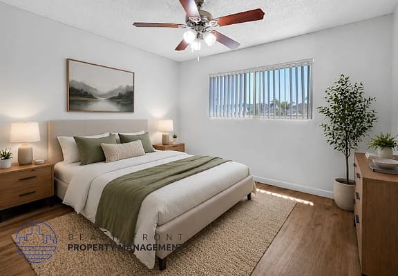 A bedroom with a bed, nightstands, a ceiling fan, and a painting on the wall.